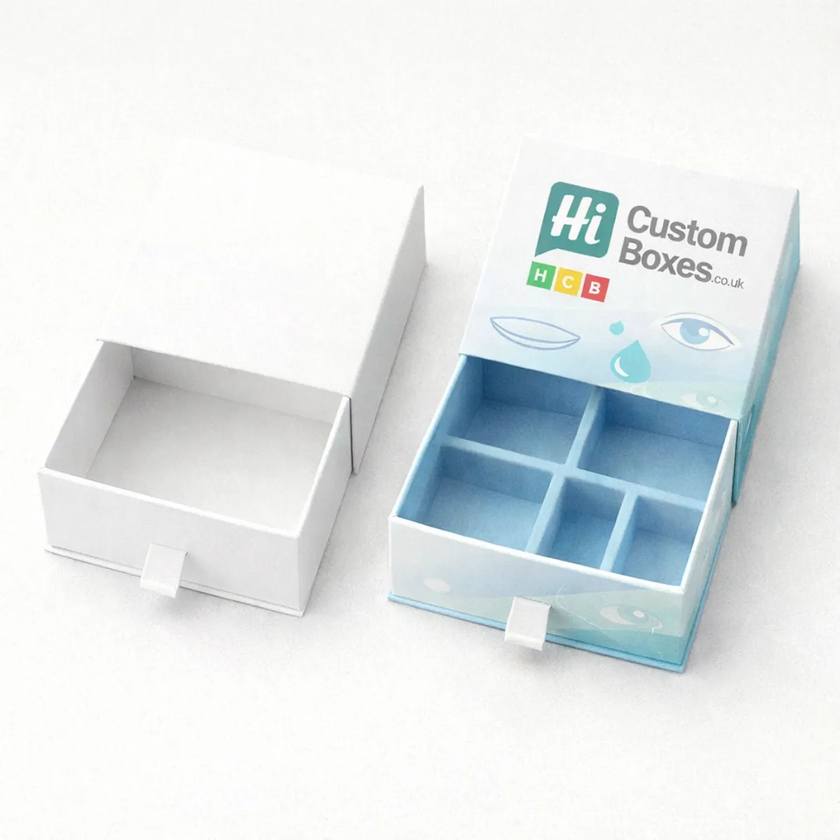 Drawer-style slide boxes- one plain white and one with a light blue eye-themed design and internal dividers- class=